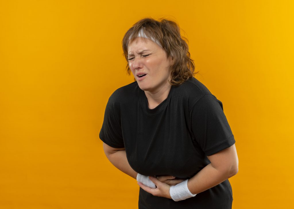 mittelalte Frau, die sich vor Schmerzen an den Bauch greift