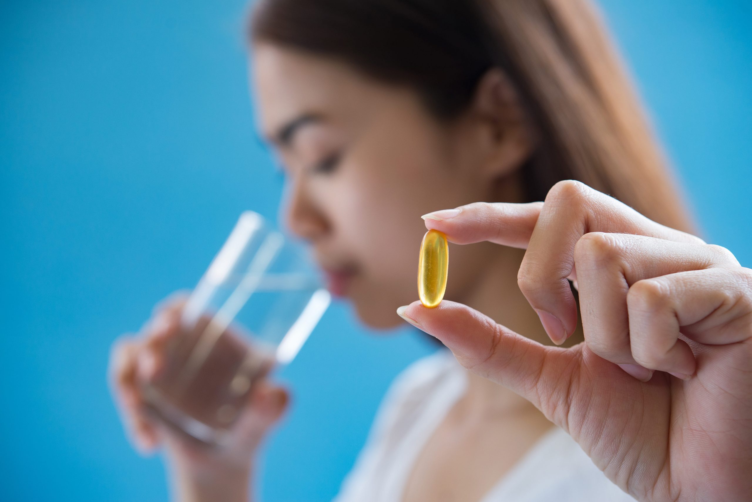 Frauen nehmen Vitamin-D-Kapseln mit Wasser.